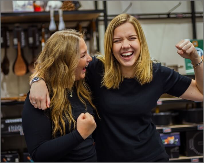 Emma og Malene holder hinanden skulder om skulder og smiler