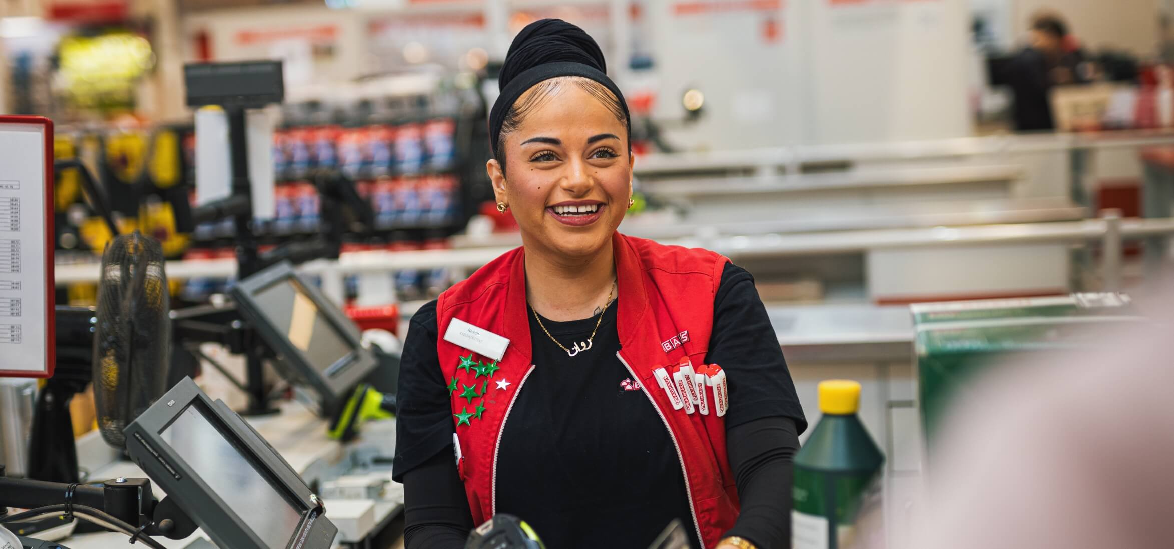 Rawan der sidder ved kassen og smiler stort