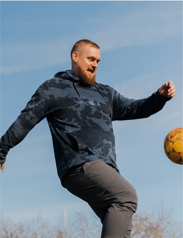 Niklas, mandlig pædagog, dribler med en fodbold udenfor under blå himmel
