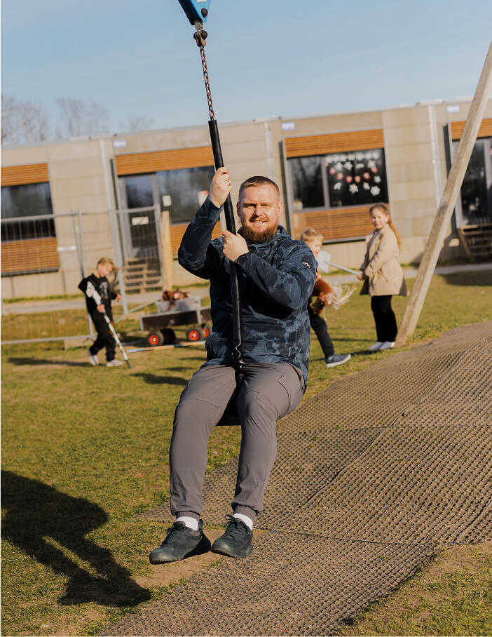 Niklas, mandlig pædagog, prøver en svævebane med børn i baggrunden