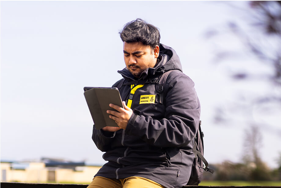 Moon sidder udenfor i sin Amnesty jakke og kigger på sin iPad
