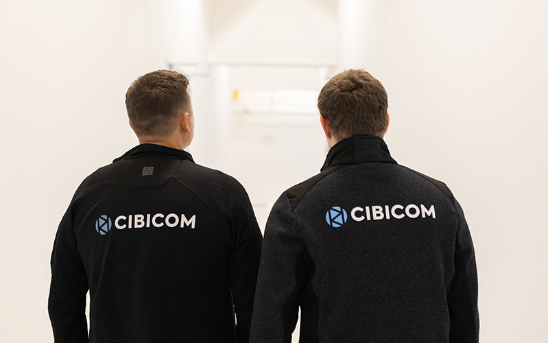 to kollegaer med ryggen til kameraet, hvor cibicom logoet er på jakkerne