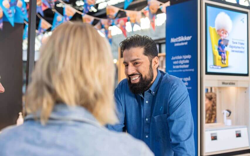 Mandlig medarbejder taler smilende til kunde