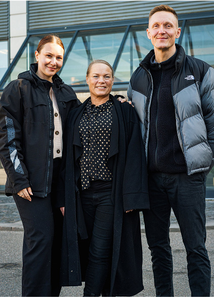 3 Xellia kolleger står foran indgangen og kigger mod kameraet.