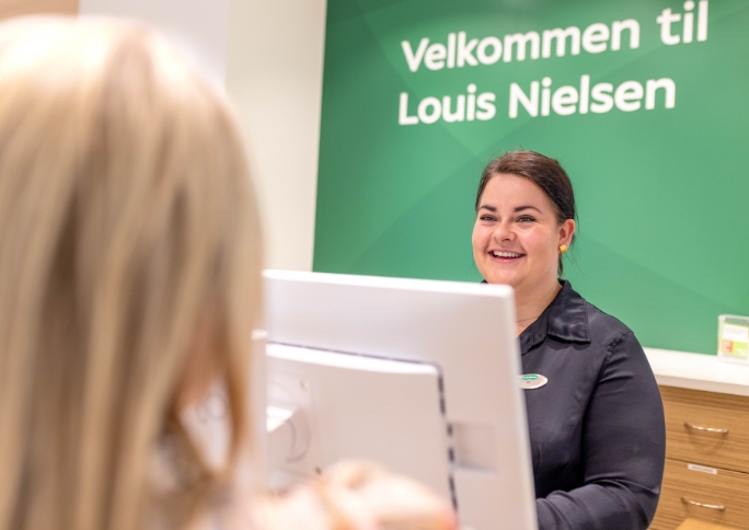 Siv står ved disk og servicerer kunde