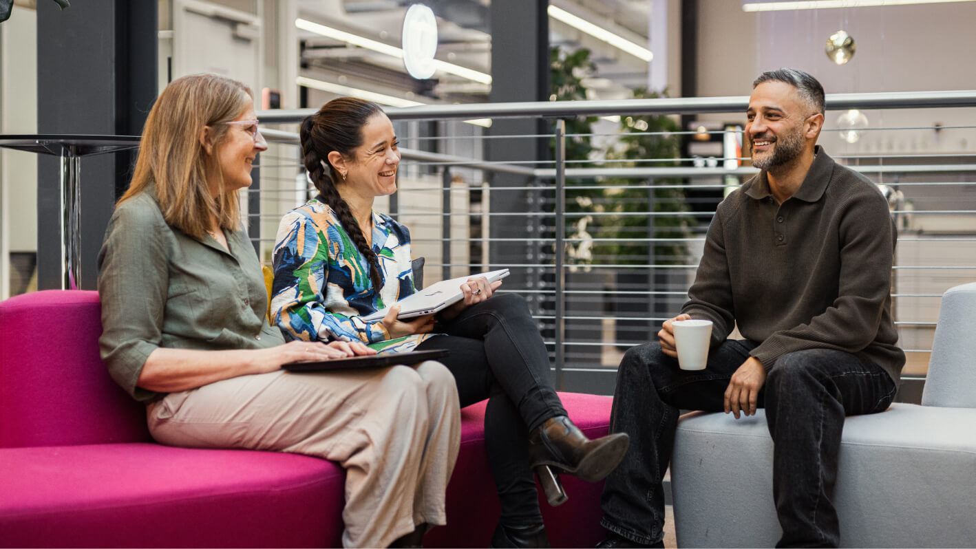 To kvindelige kolleger fra Staten og Kommunernes Indkøbsservice taler sammen i sofa.