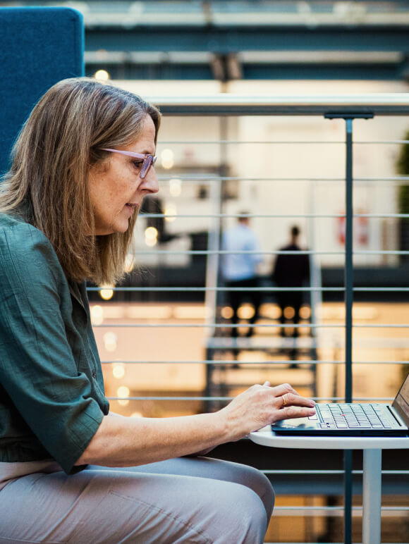 Medarbejder fra Staten og Kommunernes Indkøbsservice sidder og taster på sin laptop.
