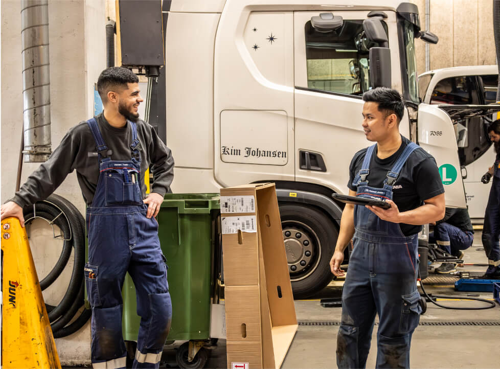 To mandlige mekanikere taler sammen og gennemgår en tablet