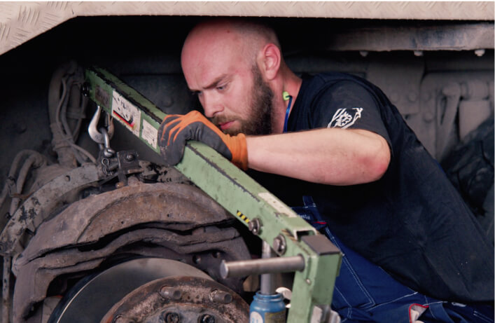 Mekaniker reparer et dæk under en lastvogn