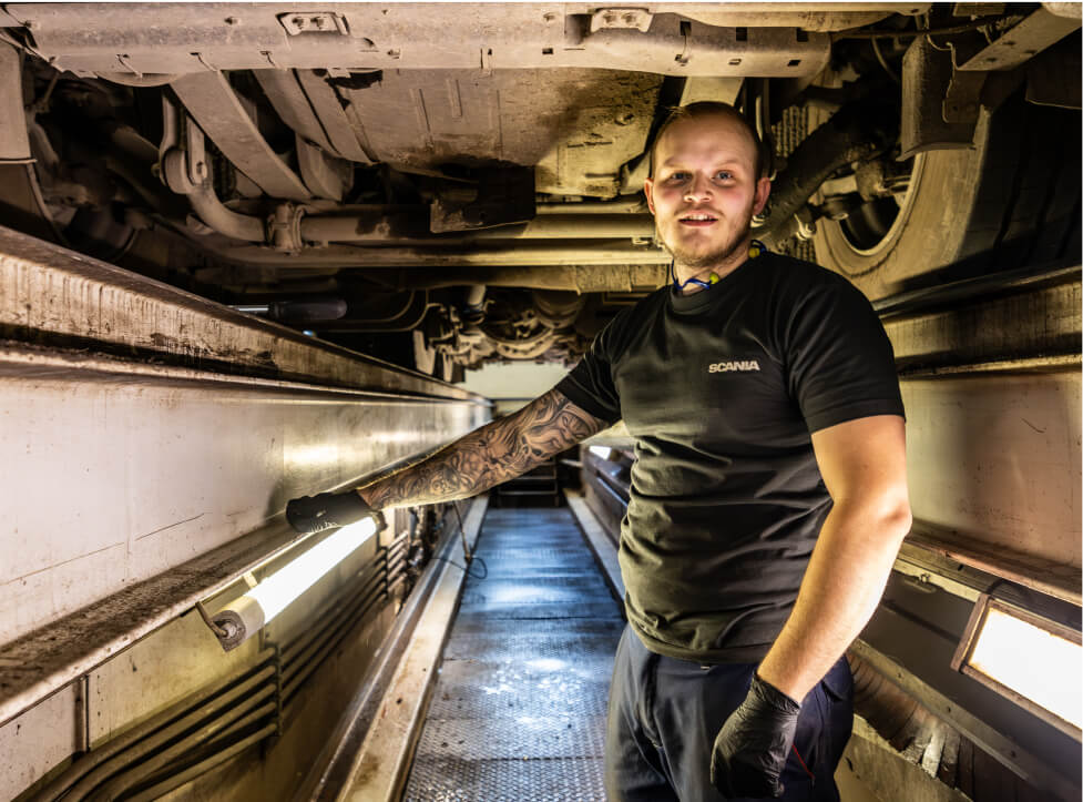 Mandlig mekaniker poserer under en lastvogn