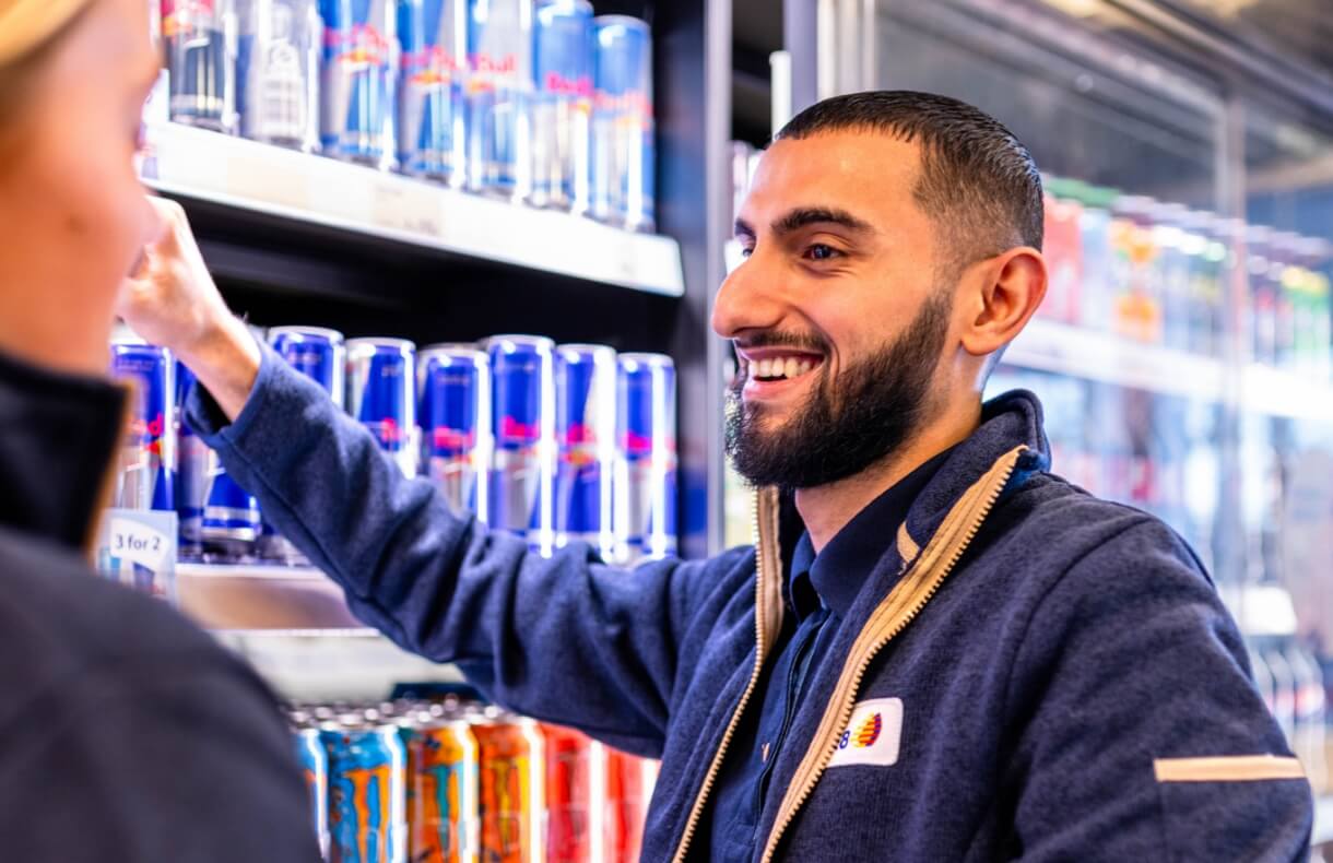 Billede af Görkem der smiler til kollega foran køledisken