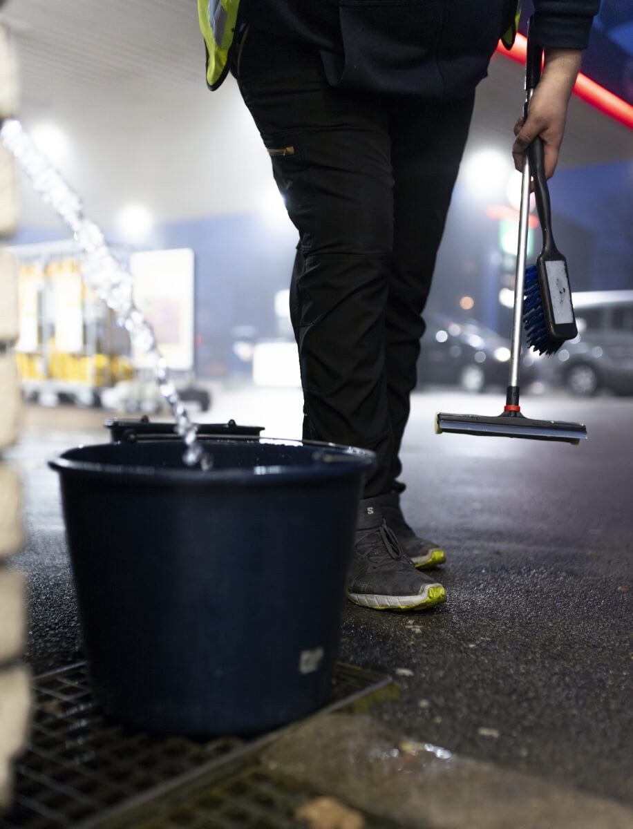 Billede af Martin der hælder vand i en spand udenfor