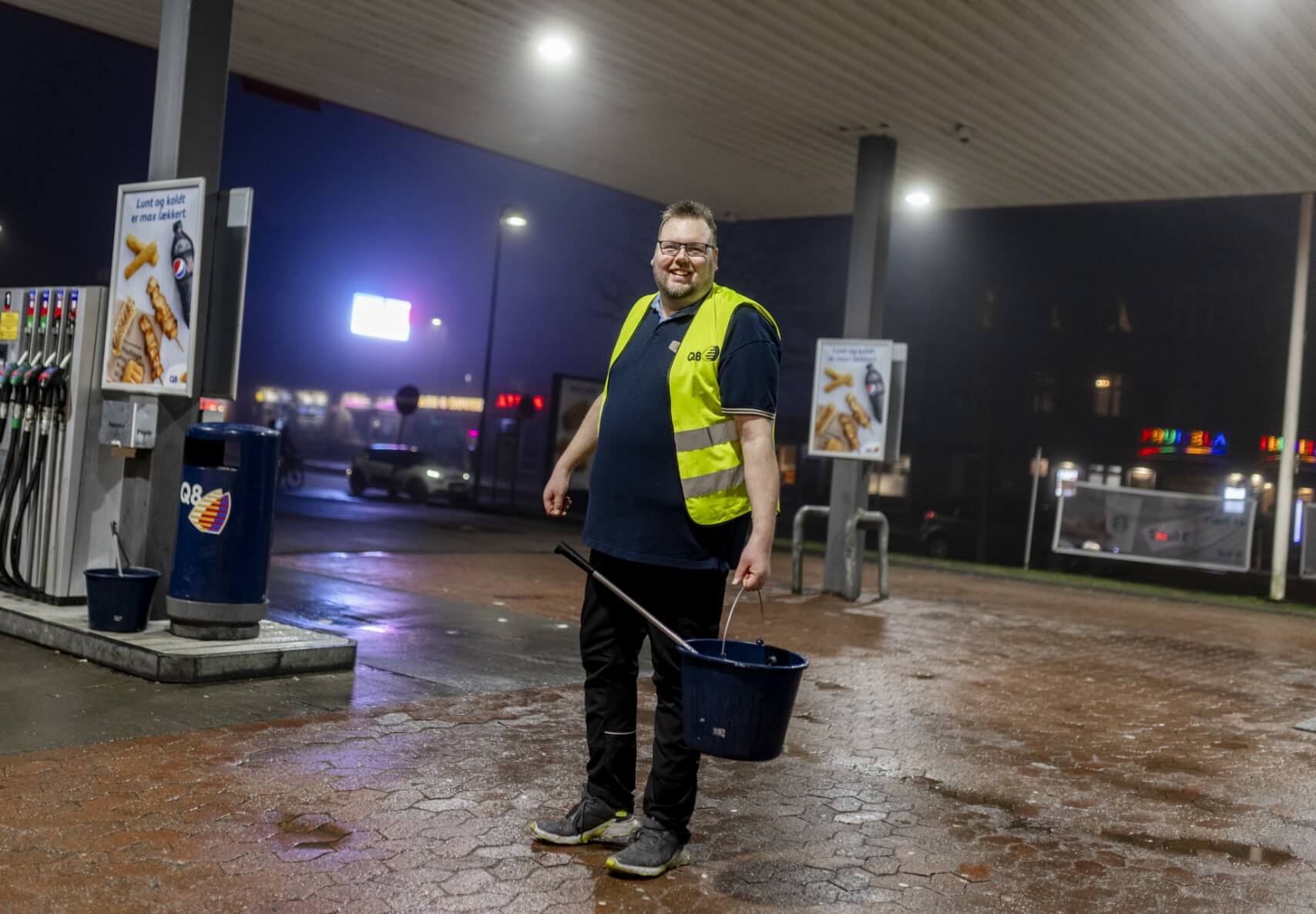 Billede af Martin der står udenfor ved stationen med en spand i hånden