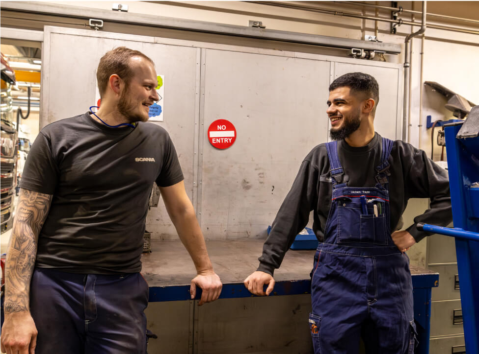 To mandlige mekanikere står og taler sammen i deres mekaniker uniform