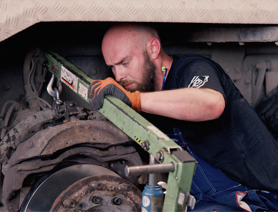 Mekaniker reparer et dæk under en lastvogn