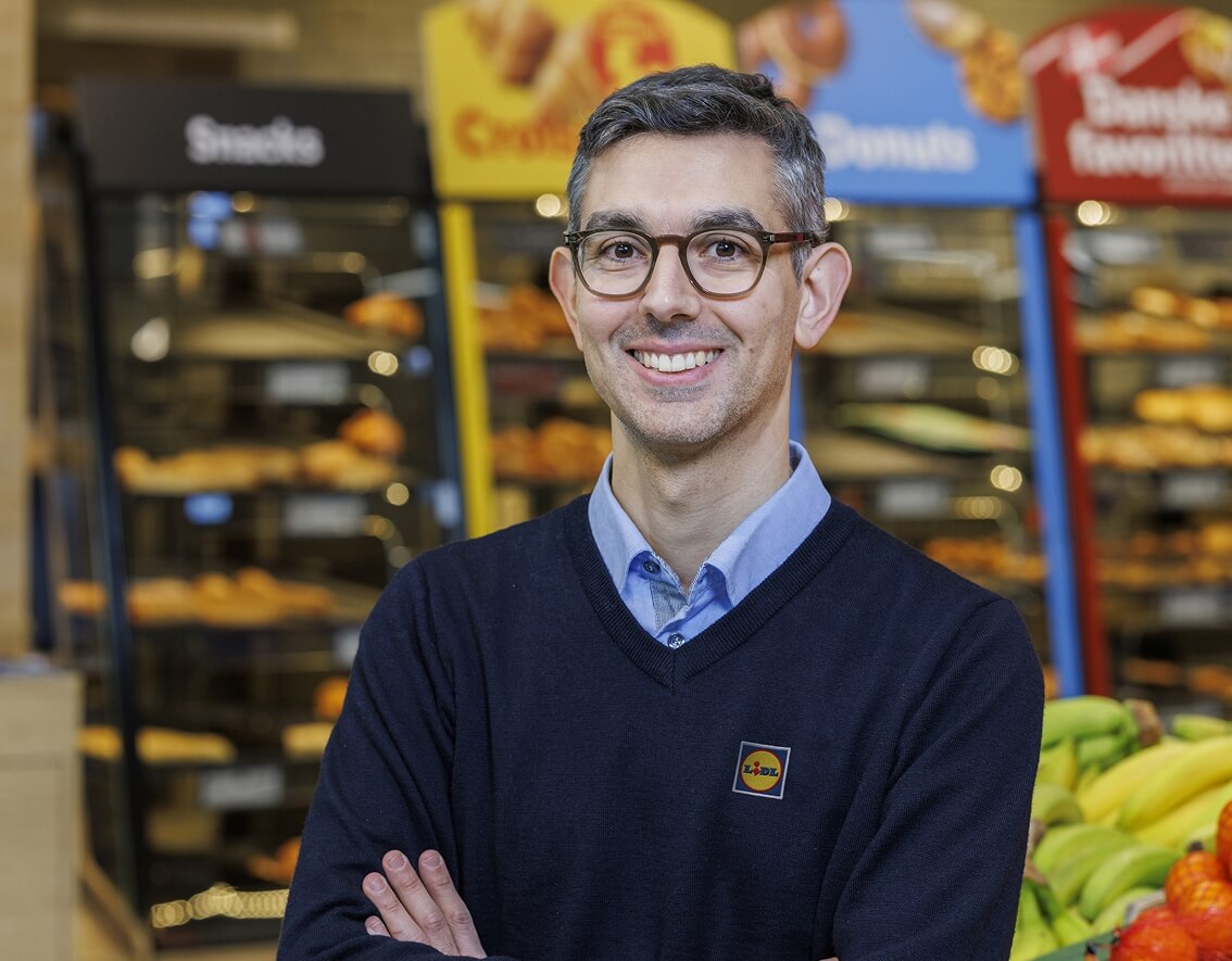 To Lidl-medarbejdere står ved siden af hinanden og smiler til kameraet
